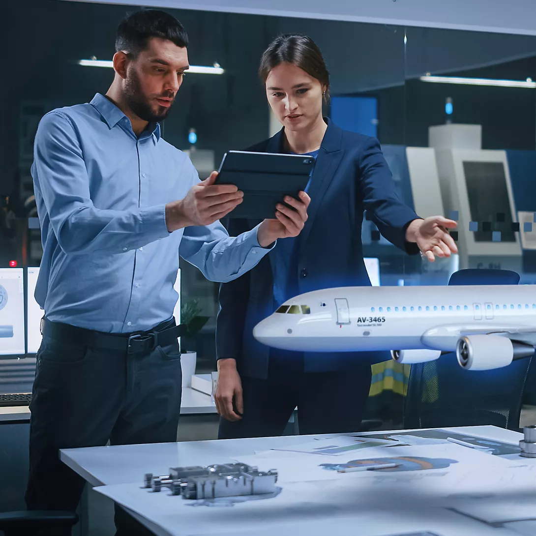 A woman and a man use a laptop to check the model of an aircraft